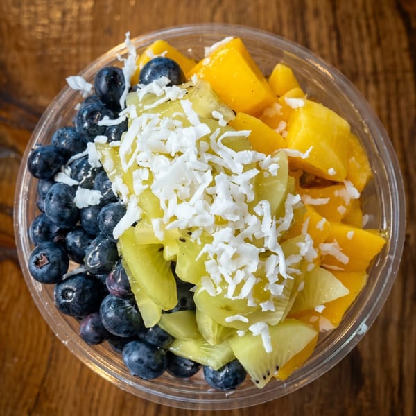 Overhead view of a fruit bowl with blueberries, mango, kiwi, and shredded coconut.